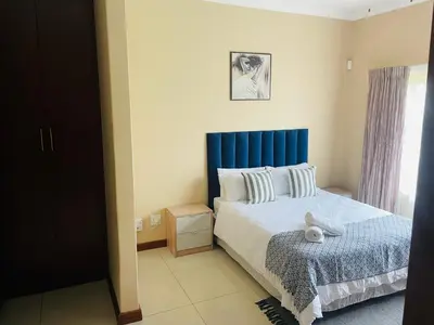 a bedroom with a bed with a blue headboard at Bela Waterfront Villa in Bela-Bela