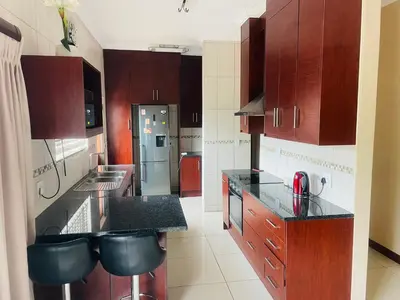 a kitchen with wooden cabinets and black counter tops at Bela Waterfront Villa in Bela-Bela