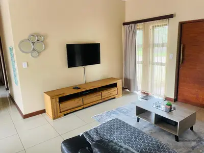 a living room with a flat screen tv on the wall at Bela Waterfront Villa in Bela-Bela