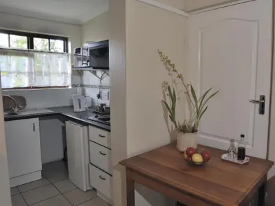 a kitchen with a table with a bowl of fruit on it at Petal Faire Cottage in Pretoria