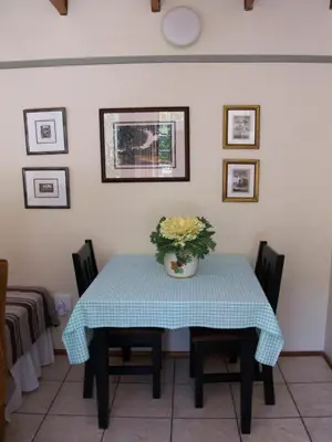 a dining room table with a vase of flowers on it at Petal Faire Cottage in Pretoria