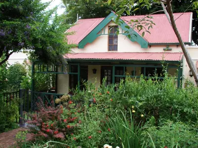 a house with a pink roof and a garden at Petal Faire Cottage in Pretoria