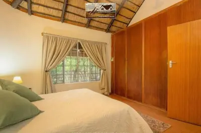 a bedroom with a large bed and a window at Nag-Apie Vakansiehuis in Marloth Park