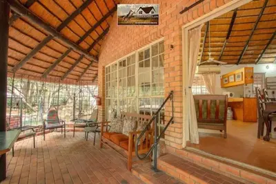 a large room with a brick wall with a table and chairs at Nag-Apie Vakansiehuis in Marloth Park