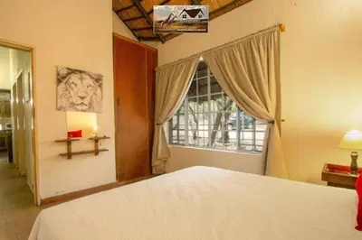 a bedroom with a large bed and a window at Nag-Apie Vakansiehuis in Marloth Park