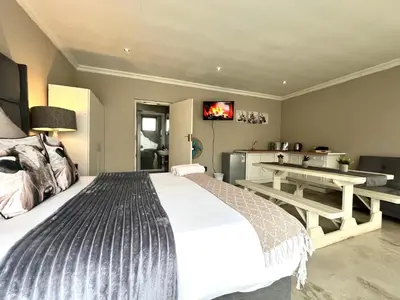 a bedroom with a bed and a table and a tv at OR Tambo Stay Unit 1 in Boksburg