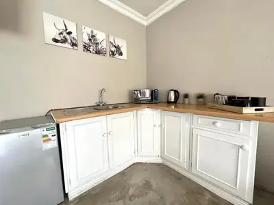 a kitchen with white cabinets and a sink and a refrigerator at OR Tambo Stay Unit 1 in Boksburg