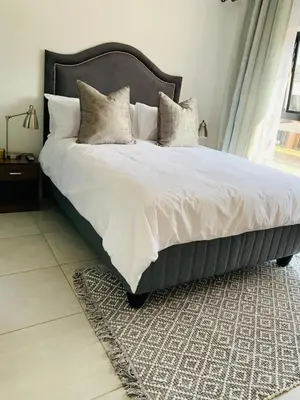 a bedroom with a large bed with white sheets and pillows at Luxury Holiday Homes - The Blyde in Pretoria