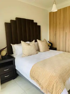a bedroom with a large bed with a large wooden headboard at Luxury Holiday Homes - The Blyde in Pretoria