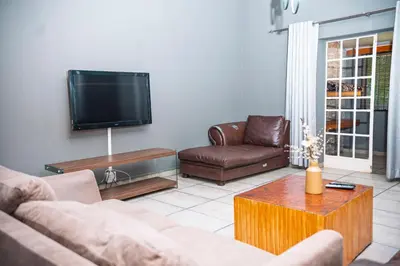 a living room with two couches and a flat screen tv at Falcon Lodge (S) in Bela-Bela