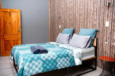 a bed with blue and white sheets and pillows at Falcon Lodge (S) in Bela-Bela