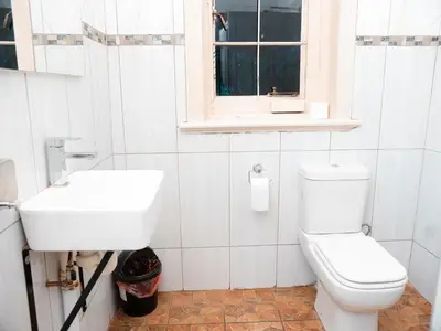 a white bathroom with a sink and a toilet at Falcon Lodge (S) in Bela-Bela