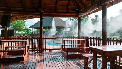 a pavilion with benches and a pool in the background at Falcon Lodge (S) in Bela-Bela