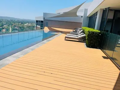 a wooden deck on a building with a swimming pool at Menlyn Maine Luxury Apartments 11th & 14th floor with Balcony in Pretoria
