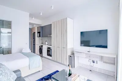 a white bedroom with a bed and a flat screen tv at Menlyn Maine Luxury Apartments 11th & 14th floor with Balcony in Pretoria