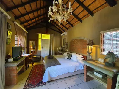 a bedroom with a bed and a chandelier at Waterhouse Guest Lodge in Waterkloof in Pretoria