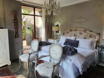 a bedroom with a bed with two chairs and a table at Waterhouse Guest Lodge in Waterkloof in Pretoria