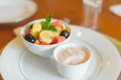 a bowl of fruit and a cup of coffee on a plate at Osborne House in Pretoria