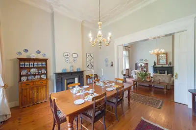 a dining room with a wooden table and chairs at Osborne House in Pretoria