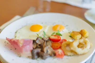 a plate of food with eggs and mushrooms on a table at Osborne House in Pretoria