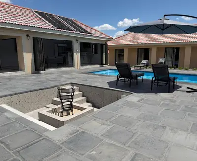 a patio with chairs and a table next to a pool at M & N Guest House in Ermelo
