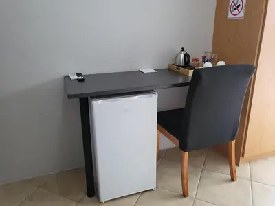 a black desk with a chair and a refrigerator at M & N Guest House in Ermelo