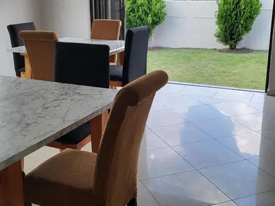 a dining room with a marble table and chairs at M & N Guest House in Ermelo