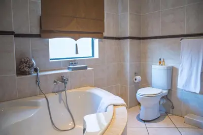 a bathroom with a tub and a toilet and a window at Casa Flora Guesthouse in Pretoria