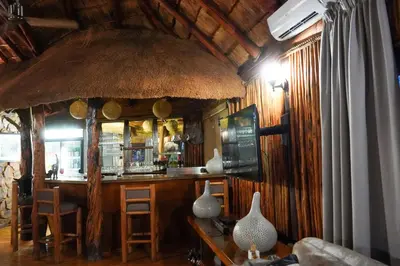 a bar in a room with a straw roof at Lucca Lodge in Musina