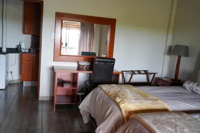 a room with two beds and a desk with a mirror at Lucca Lodge in Musina