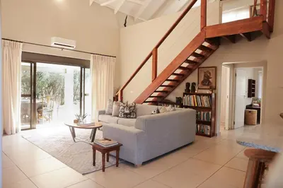 a living room with a couch and a staircase at Villa Fika Futi in Hoedspruit