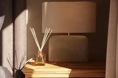 a nightstand with a lamp and a bottle of sticks at Villa Fika Futi in Hoedspruit