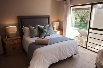 a bedroom with a large bed and a large window at Villa Fika Futi in Hoedspruit