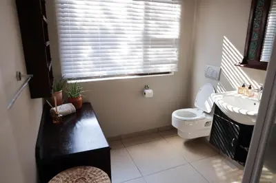 a bathroom with a toilet and a sink and a window at Villa Fika Futi in Hoedspruit