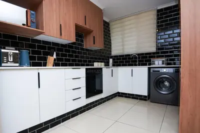 a kitchen with white cabinets and a washer and dryer at Unit 404 at Menlyn Place in Pretoria