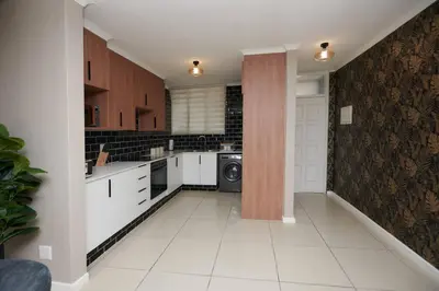 a kitchen with white cabinets and a washer and dryer at Unit 404 at Menlyn Place in Pretoria