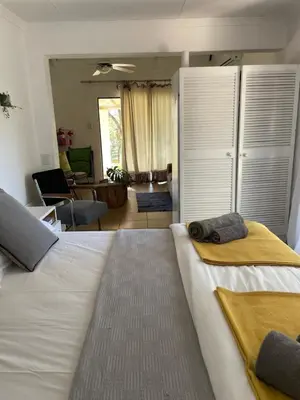 a bedroom with a large bed and a living room at Tjimaka Farm in Hazyview