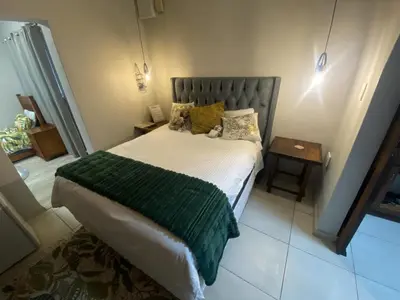 a bedroom with a bed with a green blanket at Elizabeth the 7th in Tzaneen