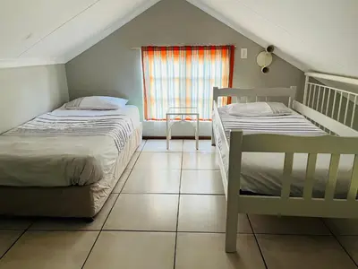 two beds in a small room with a window at Pendleberry Grove Unit 36 in Bela-Bela