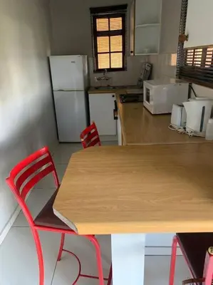 a kitchen with a wooden table and two red chairs at Pendleberry Grove Unit 36 in Bela-Bela