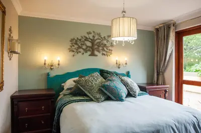 a bedroom with a blue bed with pillows on it at Strawberry Fields Country Manor Guest House in Johannesburg