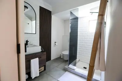 a bathroom with a shower and a toilet and a sink at The Woodpecker Inn in Pretoria