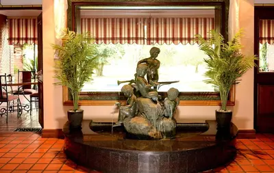 a statue in the lobby of a building with a fountain at The Woodpecker Inn in Pretoria