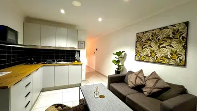 a kitchen and a living room with a couch and a table at Micro Urban Oasis 2 in Pretoria