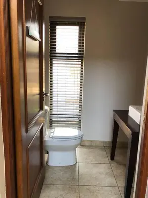 a bathroom with a toilet and a window at Golf Suites @ Copperleaf in Centurion