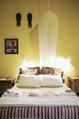 a bed with a white comforter in a room at Timbavati Safari Lodge in Mbabat