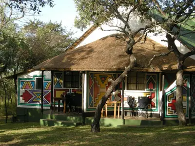 a house with a thatch roof with a table at Timbavati Safari Lodge in Mbabat