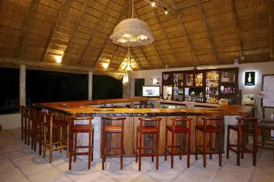a bar with wooden stools and a large island at Timbavati Safari Lodge in Mbabat