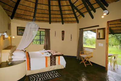 a bedroom with a bed and a desk and a window at Timbavati Safari Lodge in Mbabat