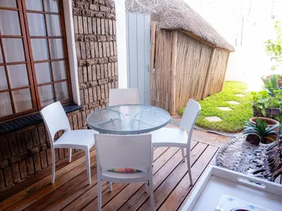 a patio with a glass table and white chairs at Sleepers Villa Guesthouse in Polokwane